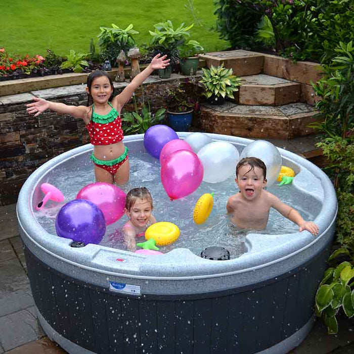 Children playing with colorful balloons in an outdoor hot tub.