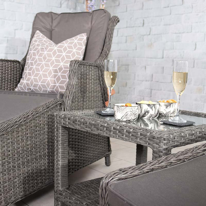 This image shows the side view of the Paris Recliner Set, complete with decorative pillows and a glass-top table with champagne and snacks.