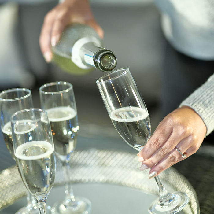 A close-up image capturing a hand pouring champagne into flutes on the Paris Deluxe Modular Corner Dining Set, highlighting a moment of celebration.