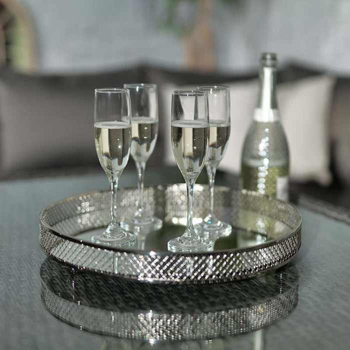 A close-up of champagne glasses on a tray atop the glass table of the Paris Deluxe Modular Corner Dining Set, perfect for entertaining guests.