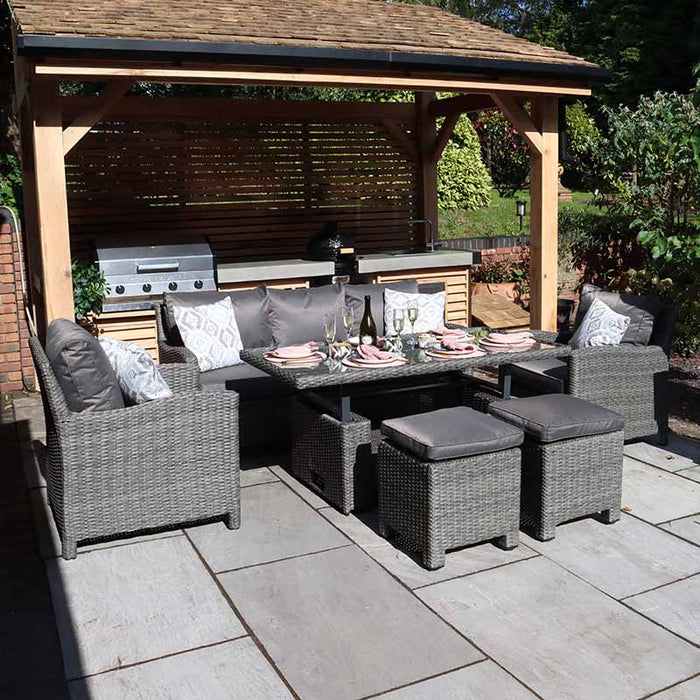 Front-facing view of the Paris 7 Seater Deluxe Sofa Dining Set, with grey cushioned chairs and stools around a glass-topped dining table, all under a stylish wooden pergola. Perfect for alfresco dining and social gatherings.