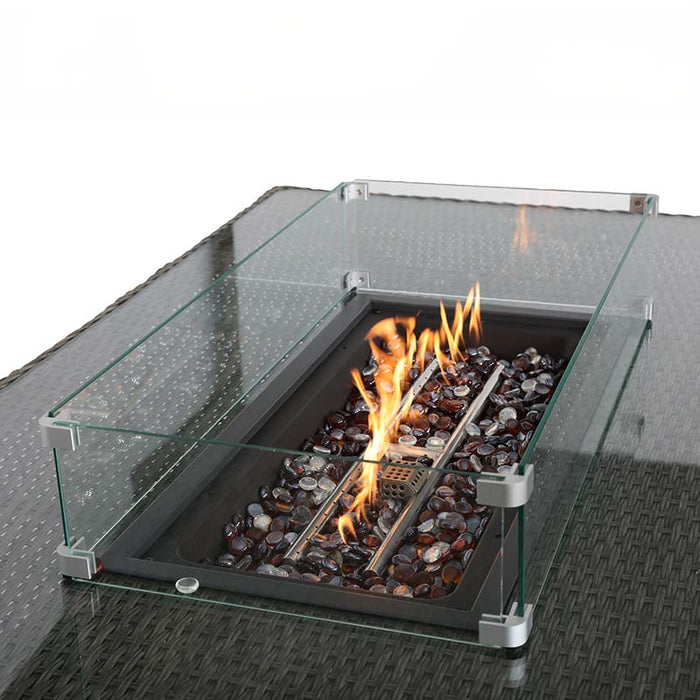 A close-up view of the Paris Corner Dining & Lounge Set's fire pit, with flames dancing over decorative stones within the glass surround.