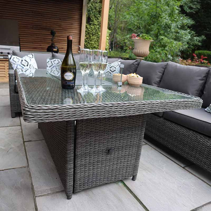 A stylish outdoor arrangement showcasing the Paris Fire Pit Corner Dining & Lounge Set, with its sleek rectangular table and comfortable seating under a shaded area.