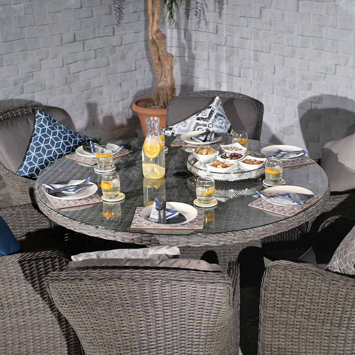 The full Paris Imperial Round Dining Set arranged outdoors, with six rattan chairs around the round glass-top table, ready for an elegant alfresco meal.