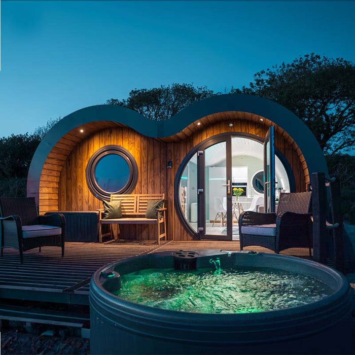 Evening view of a hot tub on a deck with a circular wooden cabin.