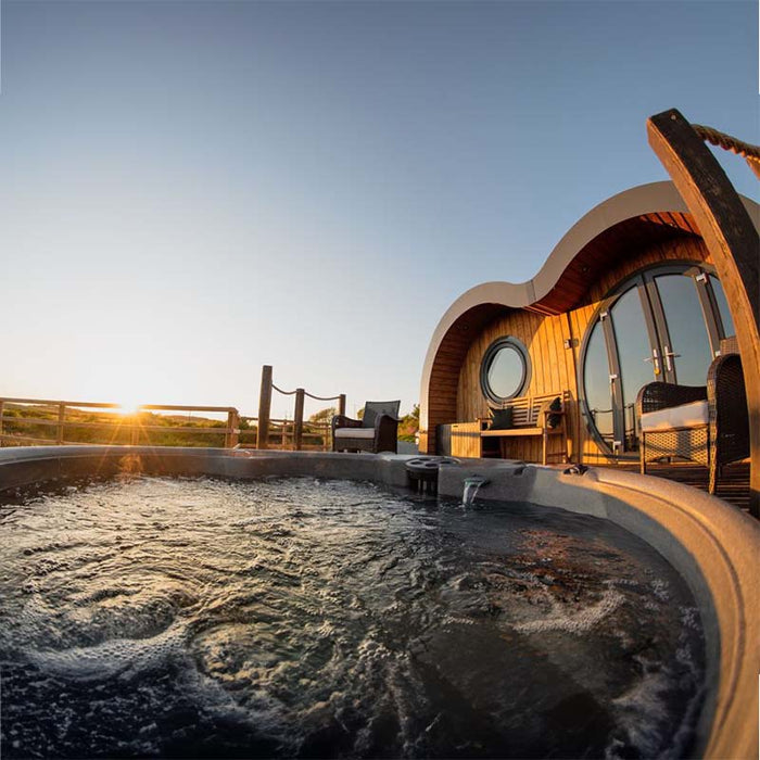 Hot tub with bubbling water at sunset in a holiday park setting.