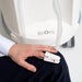 ReOxy Hypoxic Therapy Device pulse oximeter finger clip worn on a hand resting on knee, white ReOxy unit visible in background, clinical setting.