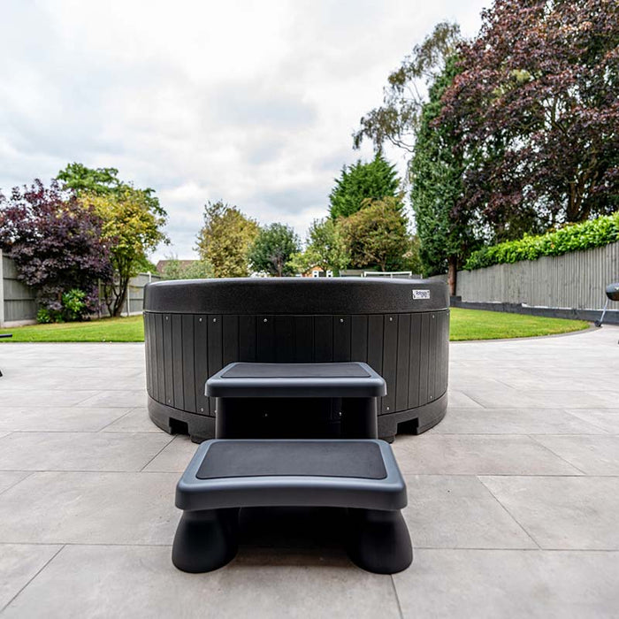 Front view of Rotospa Orbis Hot Tub with easy access steps on a modern tiled patio.