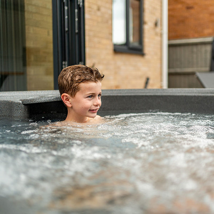 Child enjoying bubble jets and warm water fun inside the Rotospa Orbis Hot Tub.