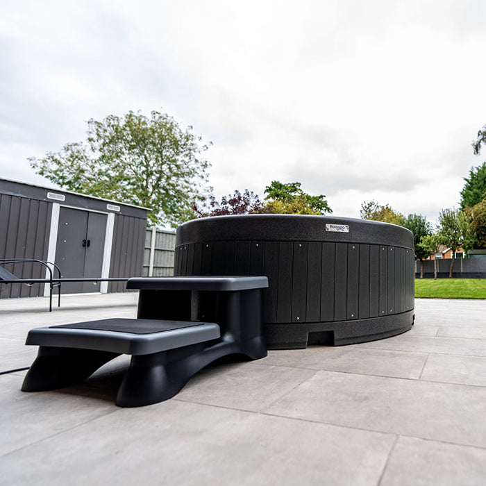 Spacious Rotospa Orbis Hot Tub with easy access steps installed on a tiled patio.