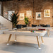 RS Barcelona Diagonal pool table with white frame and wooden legs placed in a modern loft interior with exposed brick walls, large windows and contemporary lounge seating.