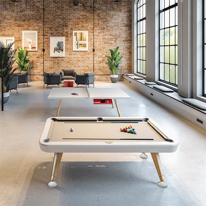 RS Barcelona Diagonal pool table with white frame and wooden legs placed in a modern loft interior with exposed brick walls, large windows and contemporary lounge seating.