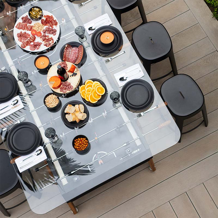 Angled top view of RS Barcelona RS Max dining football table with black stools, glass tabletop and shared dining setup, modern multifunctional indoor outdoor dining table.