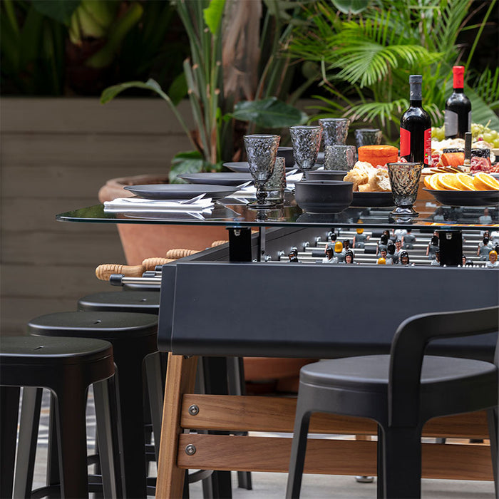 RS Barcelona RS MAX dining football table styled for outdoor dining with stools, wine, cheese and charcuterie in a modern garden patio.
