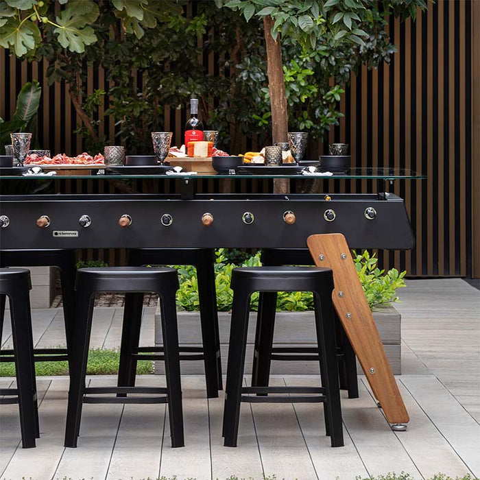 RS Barcelona RS Max dining football table outdoor setup with black stools, glass top and wooden legs, contemporary garden dining furniture with integrated foosball design