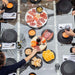 Overhead view of RS Barcelona RS Max dining football table with people dining, sharing food and drinks, stylish glass surface with integrated foosball game for social gatherings.