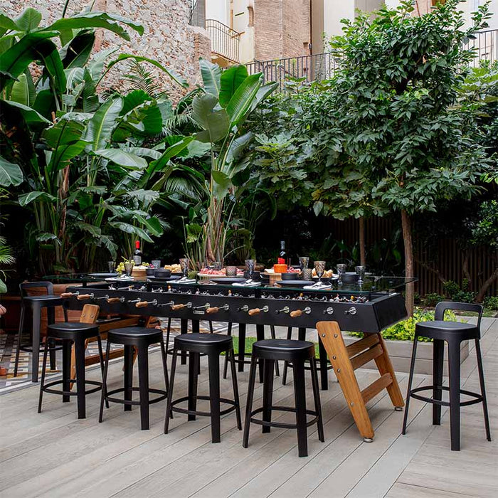 RS Barcelona RS MAX outdoor dining football table surrounded by stools and set with food and drinks for garden entertaining.