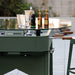 Outdoor RS Barcelona RS2 dining football table in green with glass top, featuring foosball players beneath and drinks on top, stylish multifunctional garden dining and gaming table.