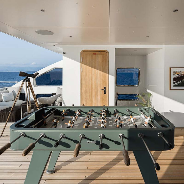 RS Barcelona RS2 football table in green placed on a luxury yacht deck overlooking the sea, showcasing premium outdoor foosball table design.