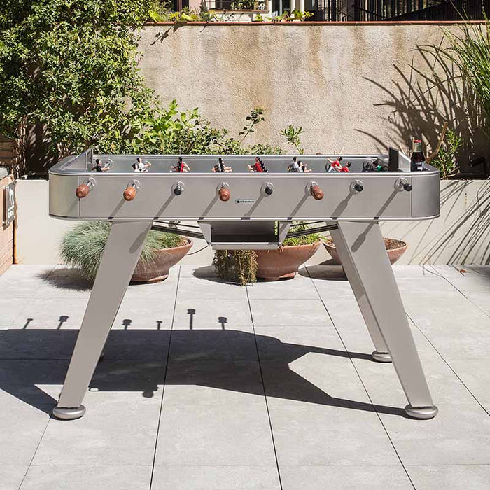 RS Barcelona RS2 football table in grey finish positioned on a modern outdoor terrace with plants and patio setting.