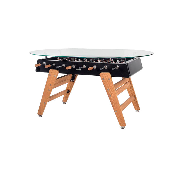 Angled view of RS Barcelona RS3 dining football table featuring tempered glass top, black metal foosball body and natural wood legs.