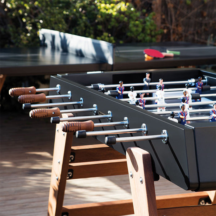 RS Barcelona RS3 Wood football table on a modern outdoor terrace with wooden legs, metal rods and ergonomic handles, creating a stylish outdoor foosball game area.