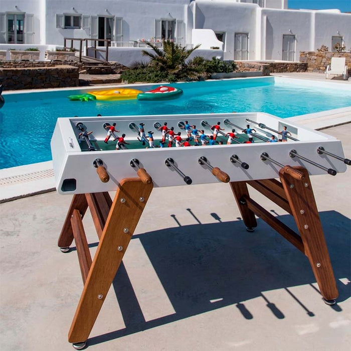 RS Barcelona RS3 Wood football table in outdoor poolside setting with white frame and solid wooden legs, premium outdoor foosball table with modern design and luxury leisure lifestyle.