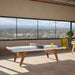Modern RS Barcelona stationary ping pong table with grey top and wooden legs in a bright loft space with panoramic windows and scenic views.