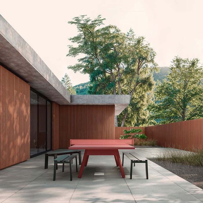 RS Barcelona You and Me monochrome ping pong table in red with benches, modern outdoor table tennis table in landscaped patio with trees and contemporary home design.