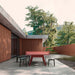 RS Barcelona You and Me monochrome ping pong table in red with benches, modern outdoor table tennis table in landscaped patio with trees and contemporary home design.