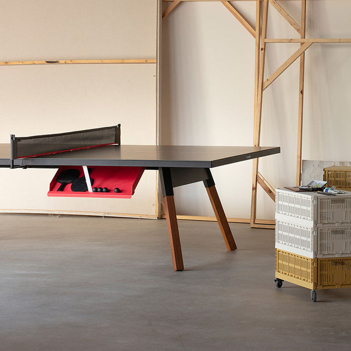 Close-up of RS Barcelona You and Me table tennis table with black surface, wooden legs and integrated paddle storage, modern indoor ping pong table design