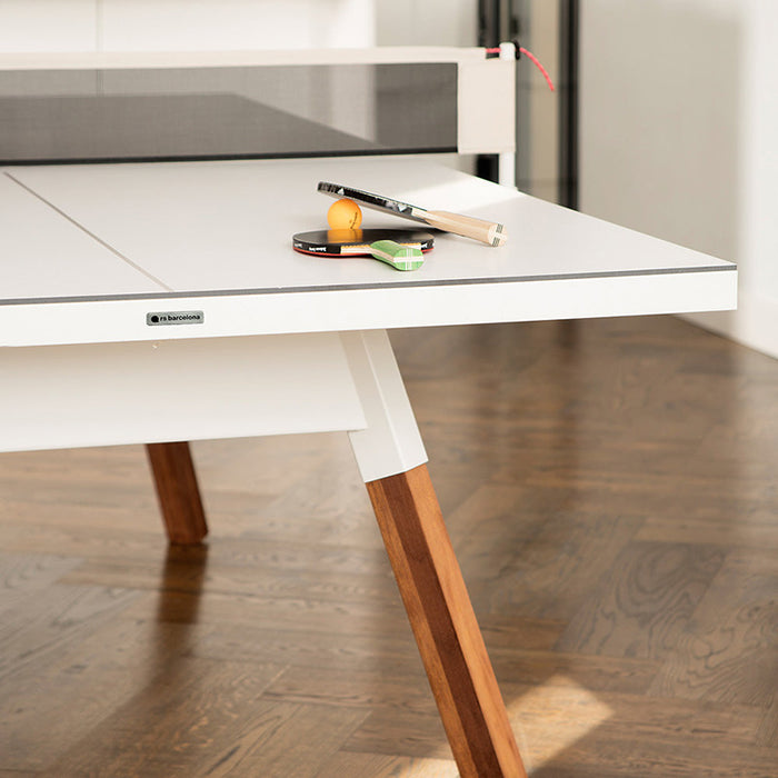 Detail of white RS Barcelona You and Me ping pong table with net, paddles and ball on surface, contemporary table tennis table with wooden legs