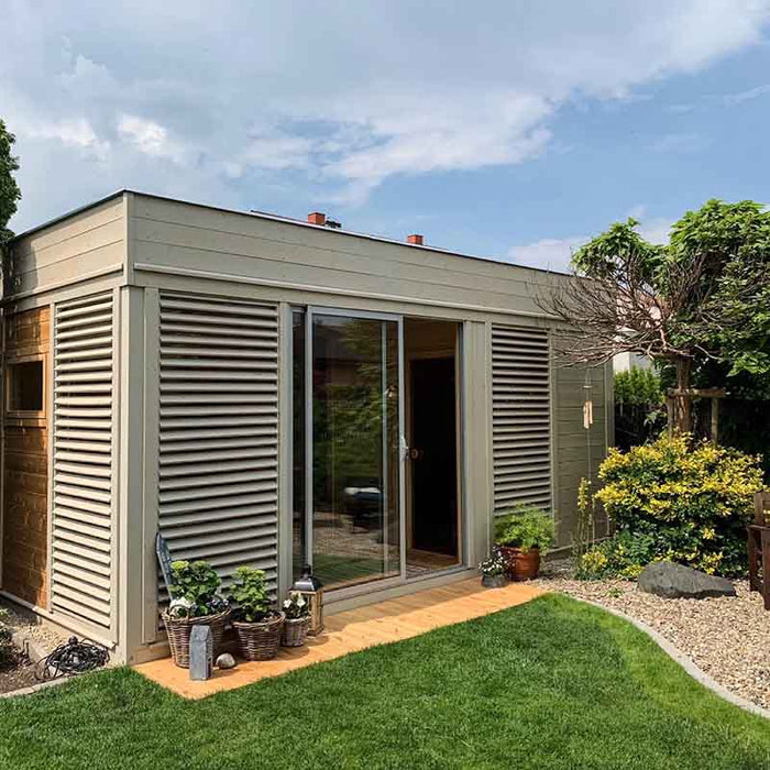 Modern traditional sauna cube with sliding glass doors and surrounding greenery.