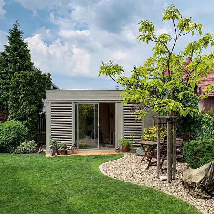 The sauna cube amidst a well-maintained garden.