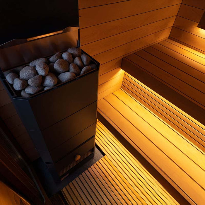 Close-up of the premium sauna heater inside the Saunum AirCube One Outdoor Sauna, surrounded by natural stones for an authentic sauna experience.