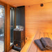 Interior view of the Saunum AirCube Terrace Outdoor Sauna, displaying the sauna heater and wooden benches, offering a functional and relaxing space.