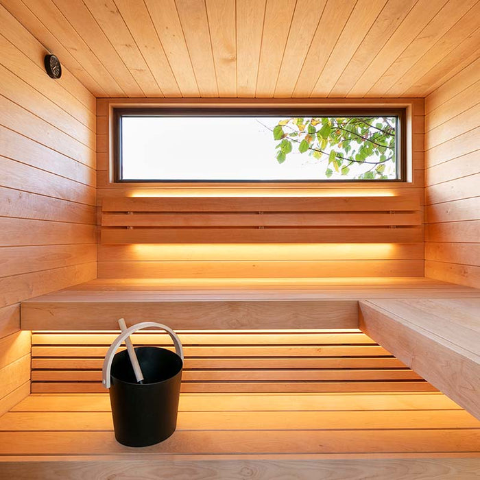 The Saunum AirCube Terrace Outdoor Sauna's wooden interior with built-in benches, soft lighting, and a large window providing natural light.