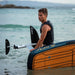SiFly Stellar blue eFoil board with wood-effect deck and hydrofoil system being carried in the sea.