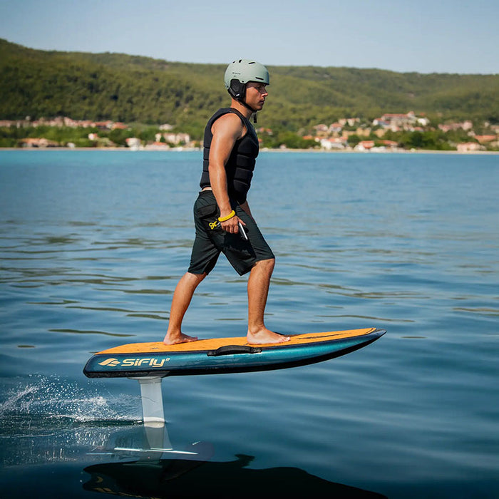 Rider cruising on a blue SiFly Stellar eFoil board with wood-effect deck and hydrofoil raised above the water.
