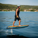 Rider cruising on a blue SiFly Stellar eFoil board with wood-effect deck and hydrofoil raised above the water.