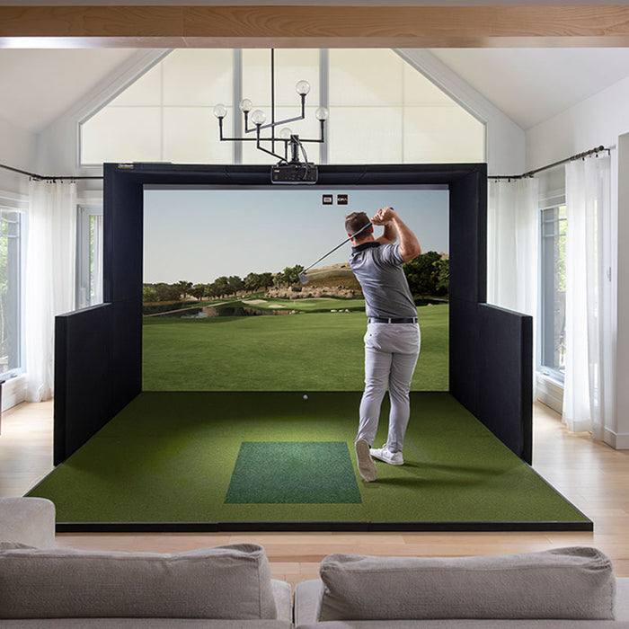 Golfer completing a swing on the Simbooth 1 Golf Simulator Kit in a bright, elegant living room setup, displaying immersive course graphics and real-time feedback.