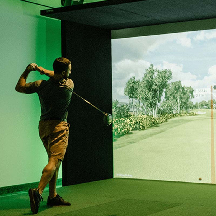 Man playing on SimBooth 2 golf simulator kit in indoor setup, with high-resolution virtual fairway projection and realistic golf tracking system for practice and training.