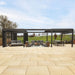 Contemporary Suns Lifestyle Luxe Electric Louvered Pergola in black, combining outdoor lounge and dining spaces on a spacious patio with scenic countryside views – a premium garden upgrade.