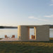 Modern Tauras Modular Air 7-person outdoor sauna cabin with curved wooden design, set on a lakeside deck with scenic water views and natural surroundings. Ideal luxury garden sauna or lakeside retreat.