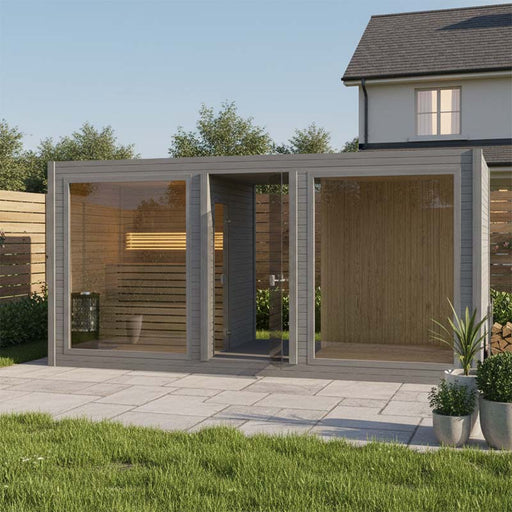 Modern Tauras Modular View 7-person outdoor sauna cabin in grey wood finish, set on a paved patio in a landscaped garden with contemporary greenery and privacy fencing.
