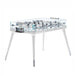 An elegant foosball table featuring a sleek glass playing surface, matte white frame, and chrome details. The players are intricately detailed, and the table stands on stylish legs.