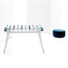 The elegant foosball table displayed in a minimalistic studio, emphasising its clear glass surface, white frame, and modern design. A blue pouffe is placed beside it.