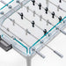 An overhead shot of the foosball table displaying its transparent glass surface, neatly arranged players, and sleek white frame.