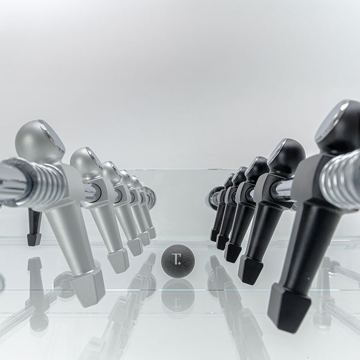 Close-up of the Teckell Cristallino Classic Foosball Table's silver and black player figures lined up with the ball in the centre.