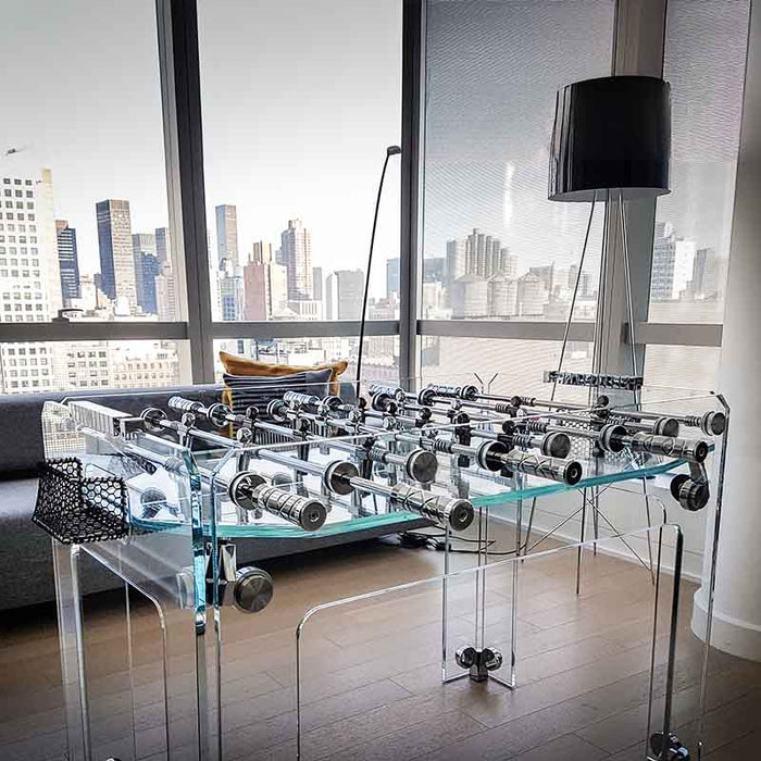 The Cristallino Classic Foosball Table set in a stylish NYC penthouse with a city view backdrop.